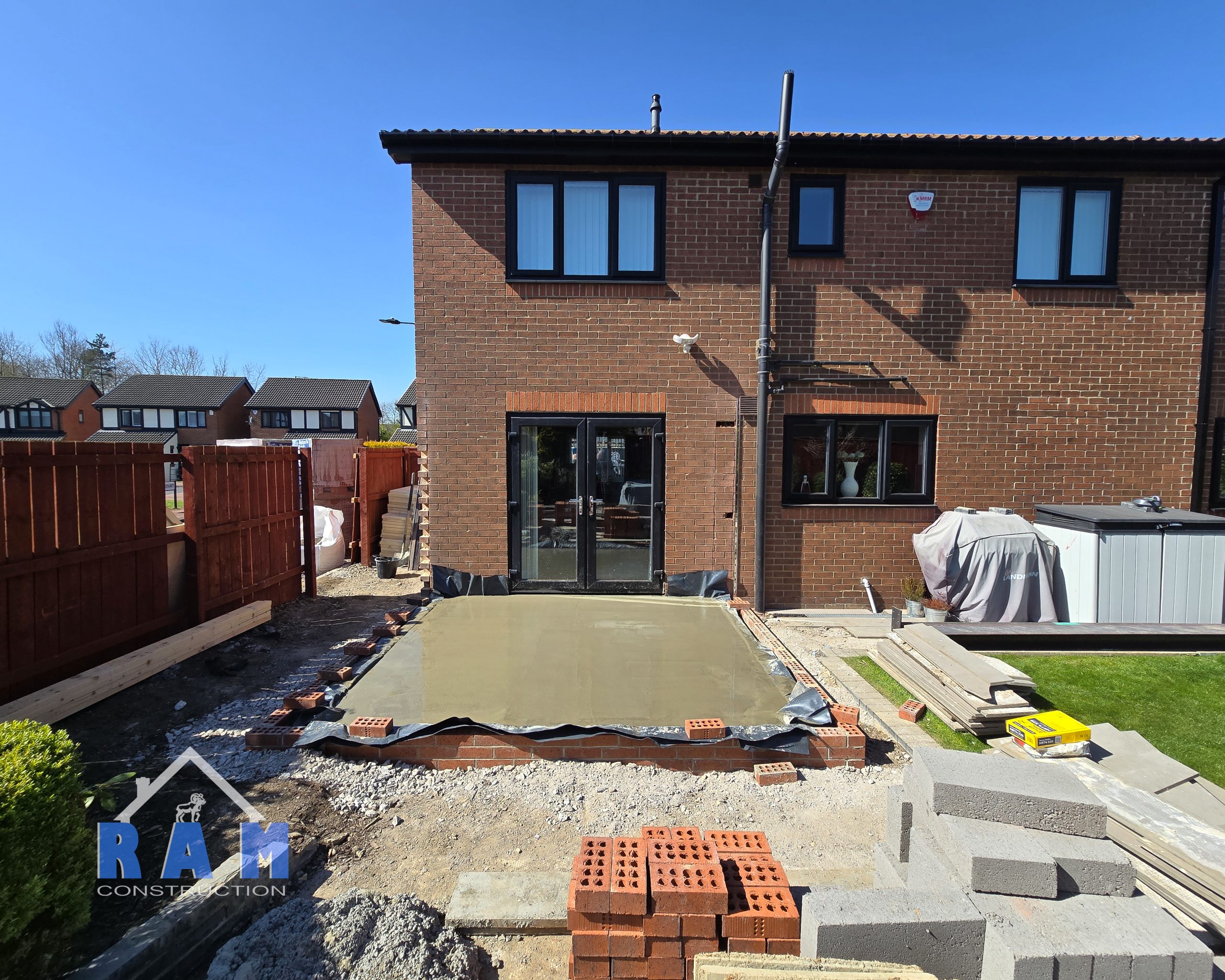 A view of where an extension will be built, there is a fresh concrete slab being poured.